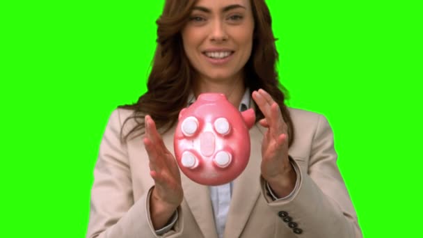 Businesswoman throwing a piggy bank on green screen — Stock Video