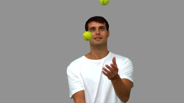 Homem driblando com bolas de tênis na tela cinza — Vídeo de Stock