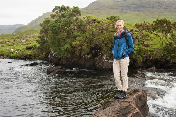 Blonde vrouw staande op een rots in een stroom — Stockfoto