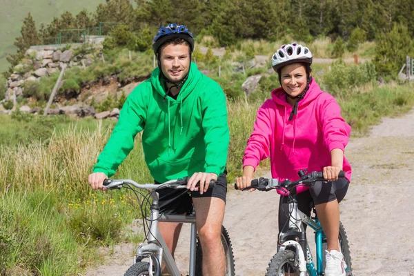 Casal feliz em um passeio de bicicleta usando camisolas com capuz — Fotografia de Stock