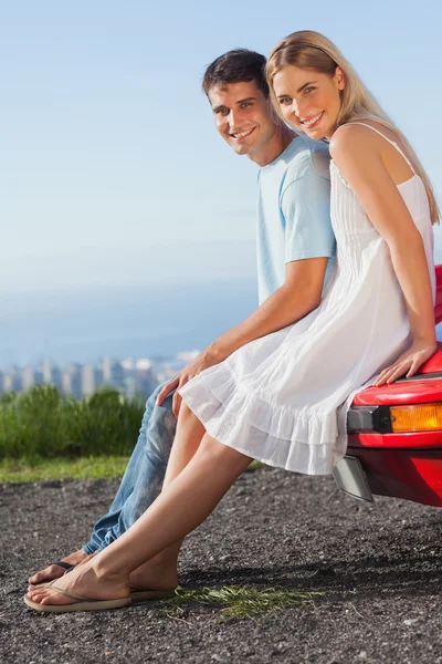 Happy couple sitting on their cabriolet car hood — Stock Photo, Image