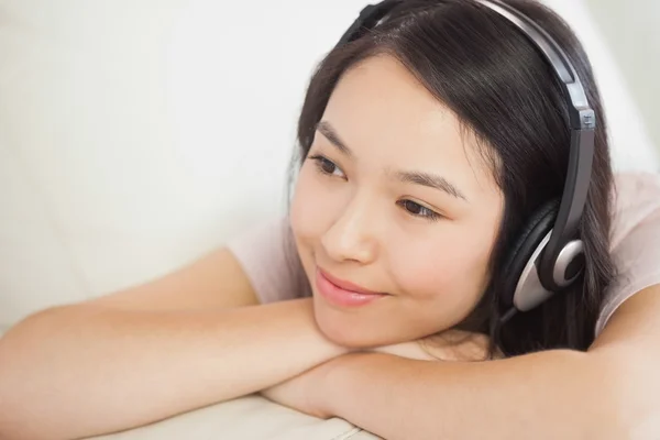 Relaxant asiatique fille couché sur l 'canapé et écouter de l' musique — Photo