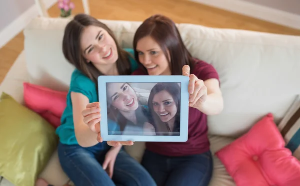 Deux amis souriants sur le canapé prenant un selfie avec tablette pc — Photo