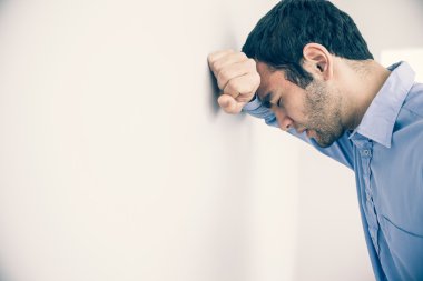 Depressed man leaning his head against a wall clipart