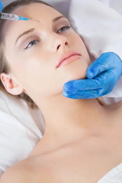 Surgeon making injection on forehead on relaxed woman lying — Stock Photo, Image