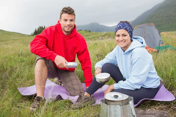 Coppia di cucina al di fuori in campeggio viaggio sorridente alla fotocamera — Foto Stock