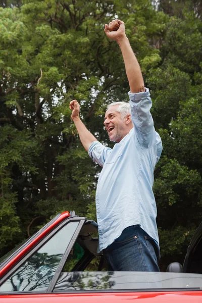 Glücklich reifer Mann genießt sein rotes Cabrio — Stockfoto