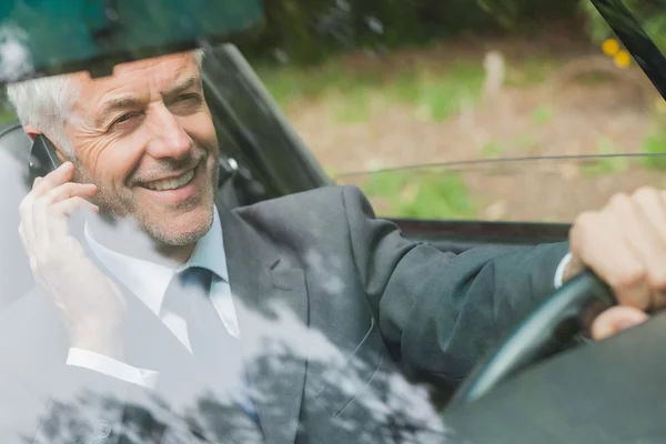 Un hombre de negocios sonriente al teléfono conduciendo — Foto de Stock