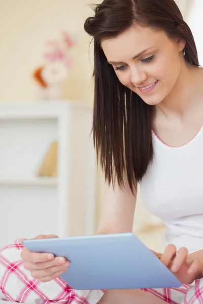 Šťastná dívka sedící na posteli pomocí tabletu — Stock fotografie