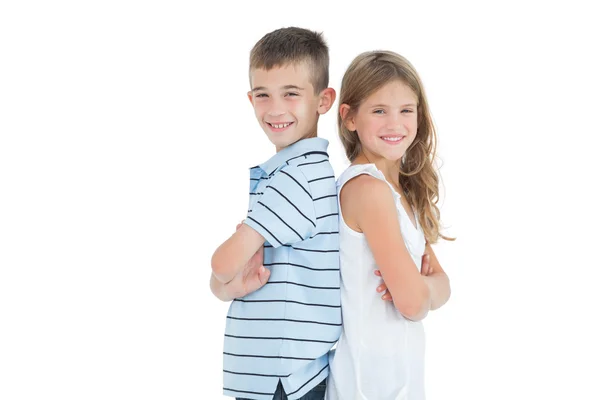 Glad ung bror och syster poserar rygg mot rygg — Stockfoto