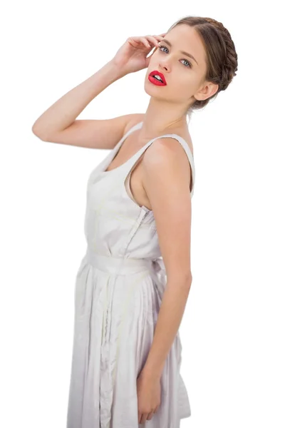 Задумчивая модель в белом платье, позирующая перед камерой — стоковое фото