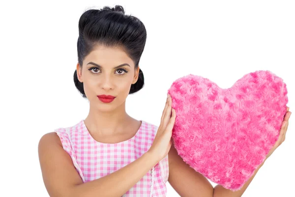 Unsmiling black hair model holding a pink heart shaped pillow — Stock Photo, Image