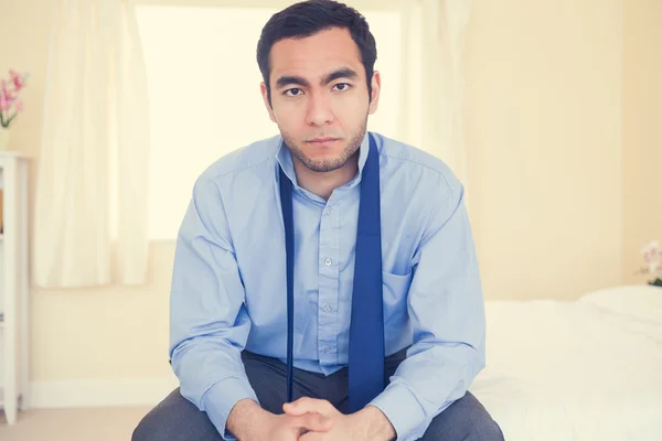 Serious man sitting on his bed — Stock Photo, Image