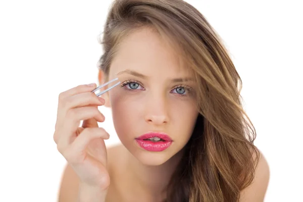 Concentrated brunette model plucking her eyebrows — Stock Photo, Image