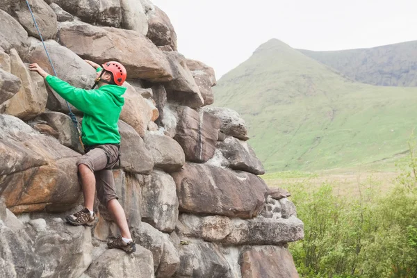 Focused man climbing a large rock face — Stock Photo, Image