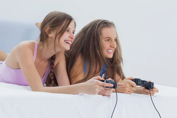 Excited girls playing video games on bed — Stock Photo, Image