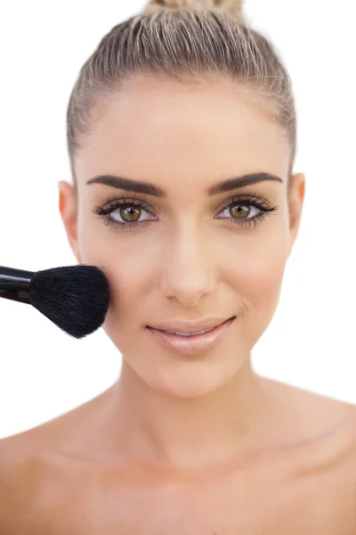 Smiling woman applying powder on her cheeks — Stock Photo, Image