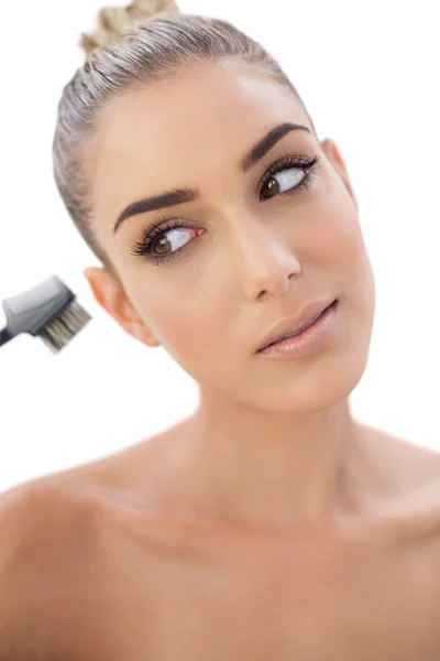 Vrouw kijken naar haar make-up borstel geconcentreerd — Stockfoto