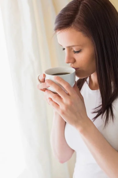 Chica pensativa sosteniendo una taza de café ojos cerrados — Foto de Stock