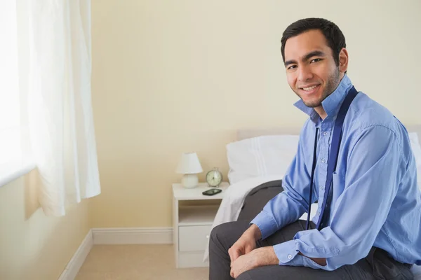 Pleased man looking at camera and relaxing sitting on his bed — Stock Photo, Image