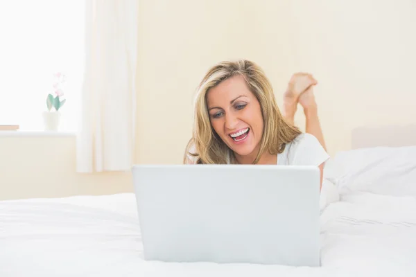 Fokussierte Frau mit Tablet-PC auf dem Bett liegend — Stockfoto