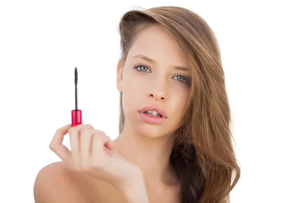 Serious brunette model holding a mascara tube — Stock Photo, Image