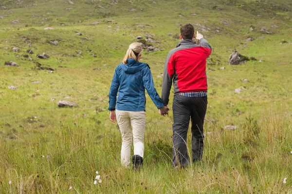 Par hålla händerna på promenad med man pekar — Stockfoto