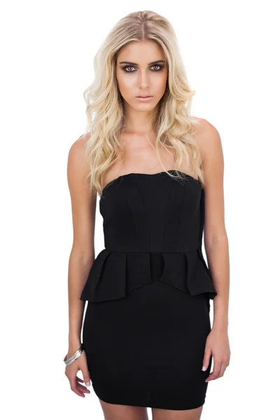 Unlächelndes blondes Model im schwarzen Kleid posiert vor der Kamera — Stockfoto