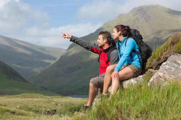 Paar nemen een pauze na bergop te wandelen met man wijzen — Stockfoto