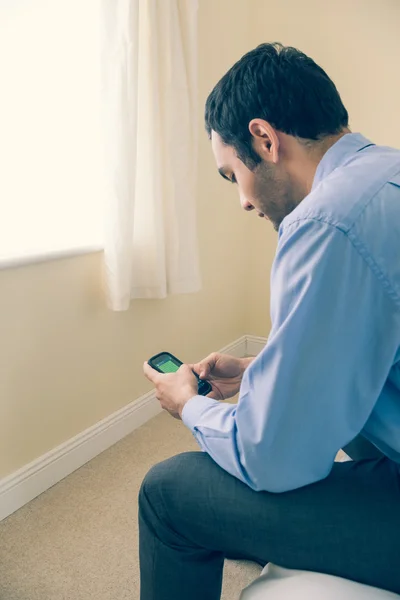 Mann mit Handy auf dem Bett sitzend — Stockfoto