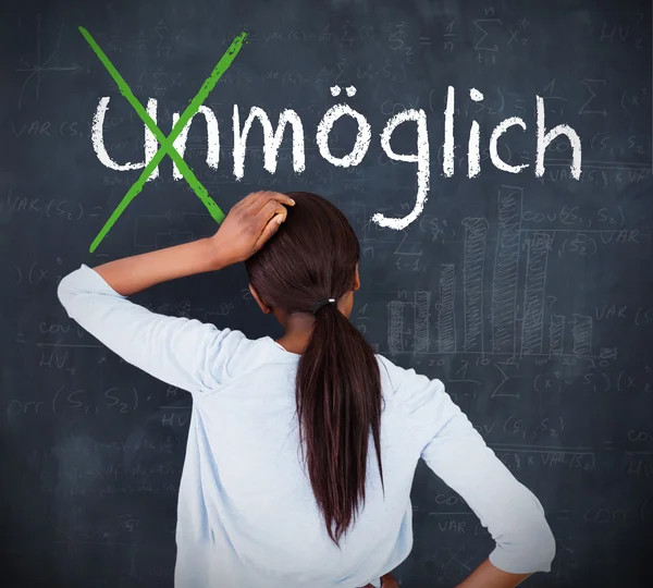 Attractive woman looking at a chalkboard with success in german on it — Stock Photo, Image