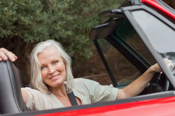 Smiling mature woman posing in red convertible — Stock Photo, Image