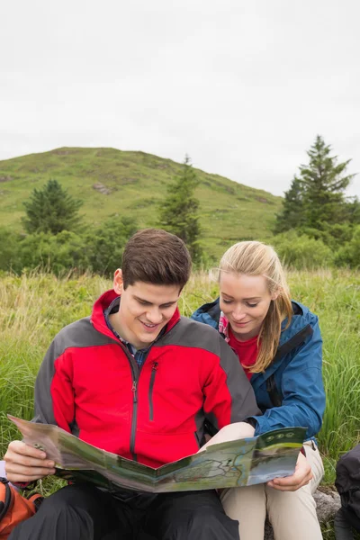 Munteres Pärchen macht Pause bei einer Wanderung, um sich die Karte anzusehen — Stockfoto