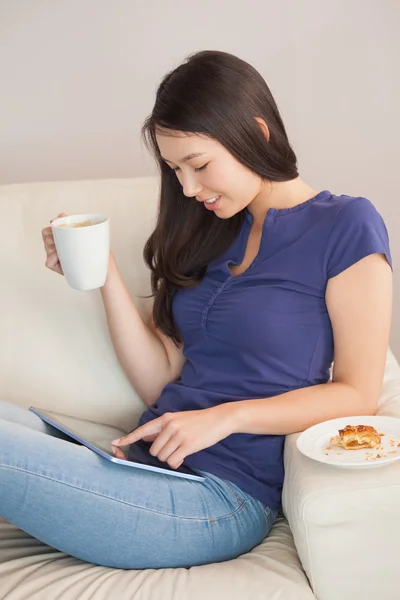 Joven mujer asiática usando su tableta pc y sosteniendo taza de café — Foto de Stock