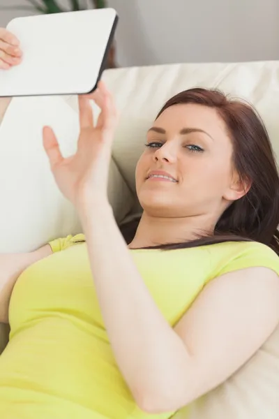 Menina adolescente feliz deitado em um sofá usando um tablet pc — Fotografia de Stock