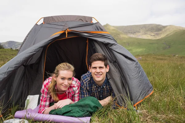 Glückliches Paar liegt nach einer Wanderung im Zelt und blickt in die Kamera — Stockfoto