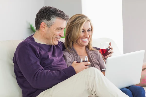 Lyckliga paret tittar på sin laptop och dricka vin — Stockfoto