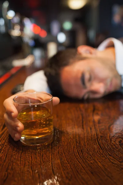 Empresario borracho sosteniendo whisky tumbado en un mostrador —  Fotos de Stock