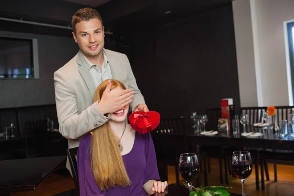 Handsome man offering present to his pretty girlfriend — Stock Photo, Image