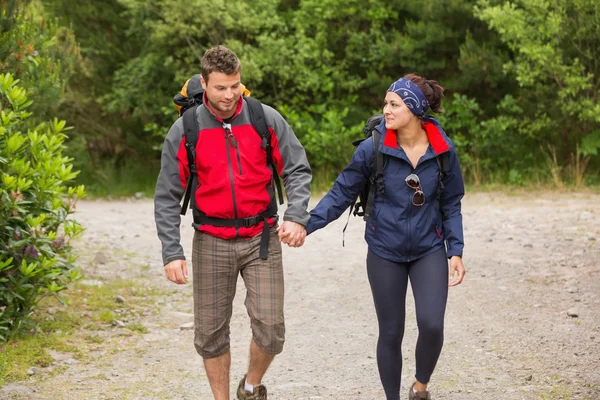 Couple souriant faisant une randonnée ensemble en se tenant la main — Photo