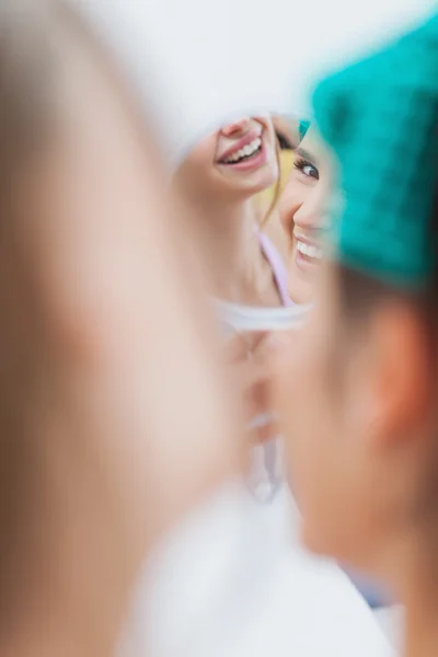 Girls sitting in bed and looking in mirror — Stock Photo, Image