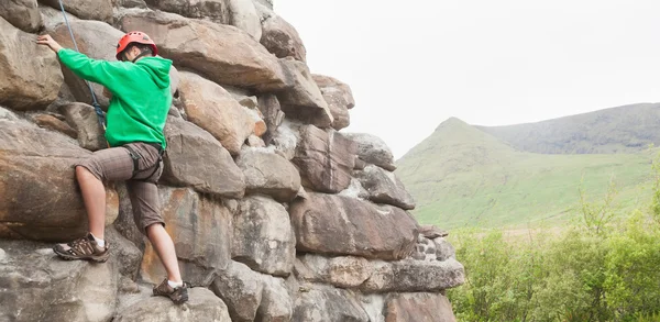 Entschlossener Mann erklettert große Felswand — Stockfoto