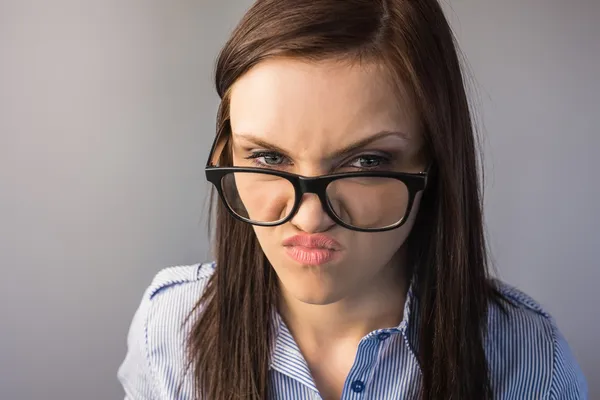 Morena séria com óculos fazendo rostos — Fotografia de Stock