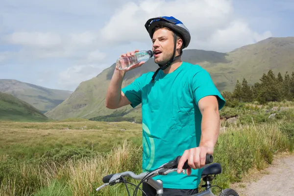 Fitter Mann stützt sich auf sein Mountainbike und trinkt Wasser — Stockfoto