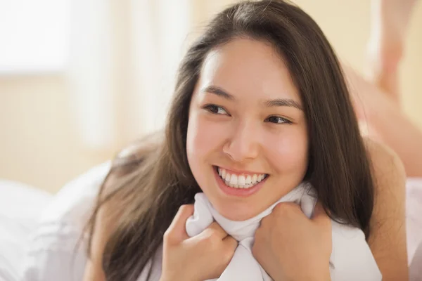Aranyos fiatal ázsiai nő tartja a paplan, és mosolyogva — Stock Fotó