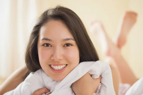 Linda joven asiática mujer agarrando su edredón y sonriendo — Foto de Stock