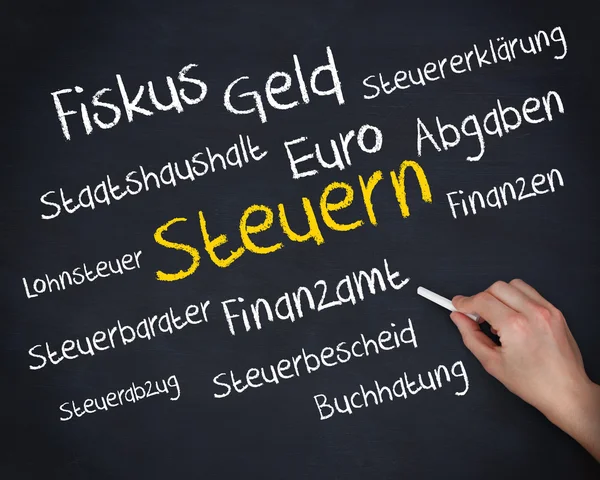 Mano sosteniendo una tiza y escribiendo varias palabras sobre impuestos en alemán —  Fotos de Stock