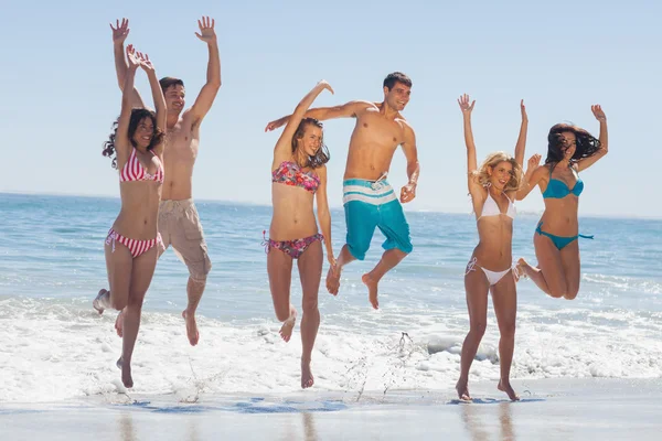 Glückliche Freunde springen am Strand — Stockfoto