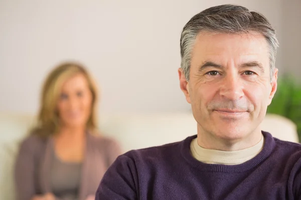 Sorridente uomo con la moglie sullo sfondo — Foto Stock