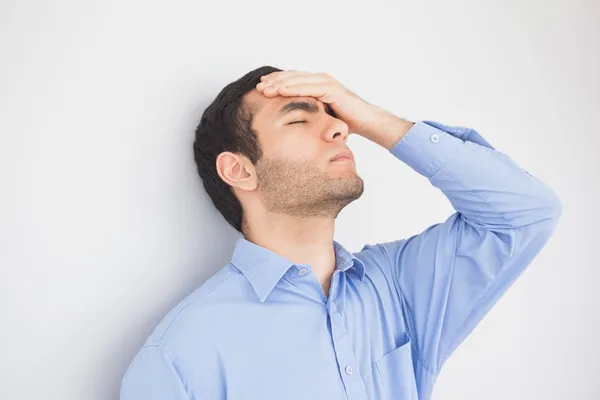 Irritated man with hand on forehead leaning against a wall — Stock Photo, Image